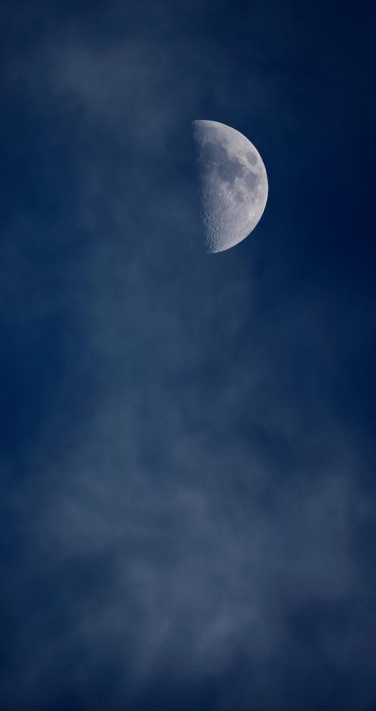 夜晚卧室里手机竖屏播放电影画面，暖黄台灯映在床头，用户半躺着单手滑动选片